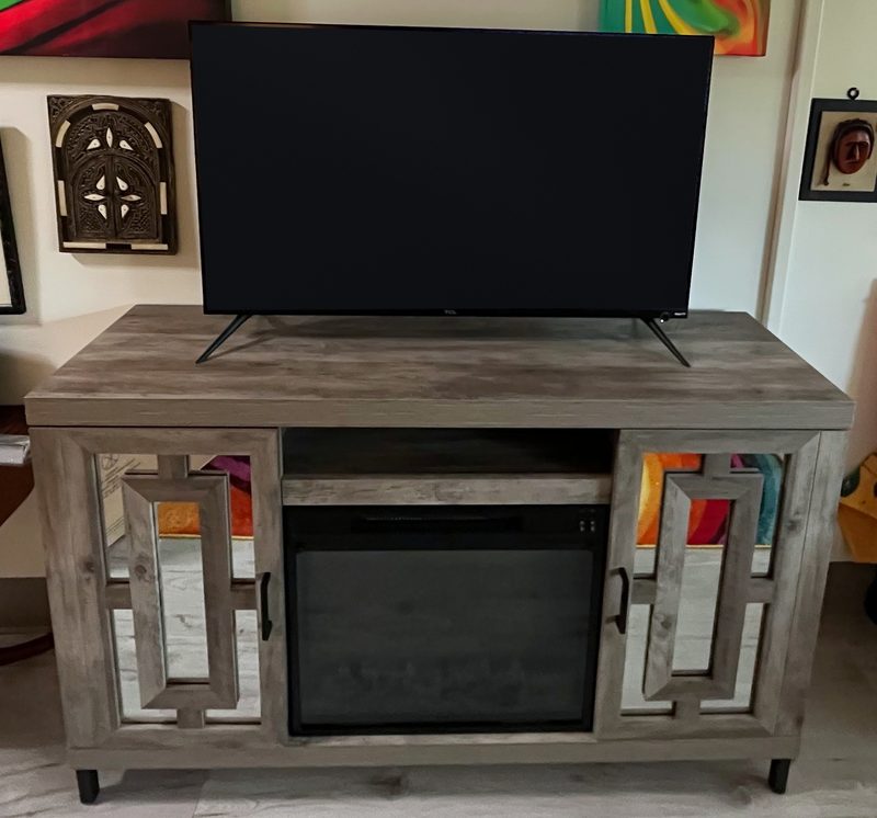 Rustic gray fireplace TV console with mirrored doors and a TV set on top